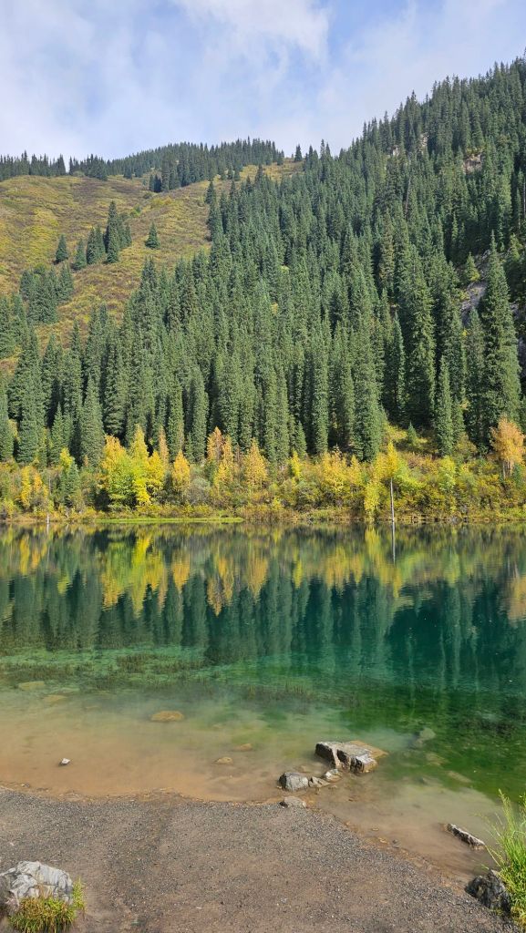 odraz jesenných stromov v azúrovom jazere Kaindy