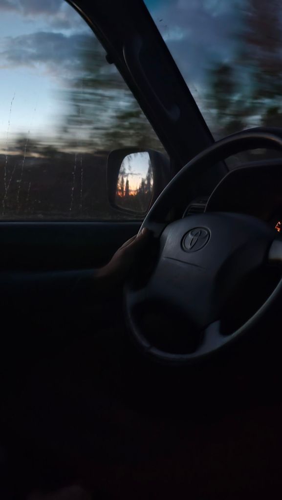 volant toyoty landcruiser a v spatnom zrkadle odraz západu slnka a stromy