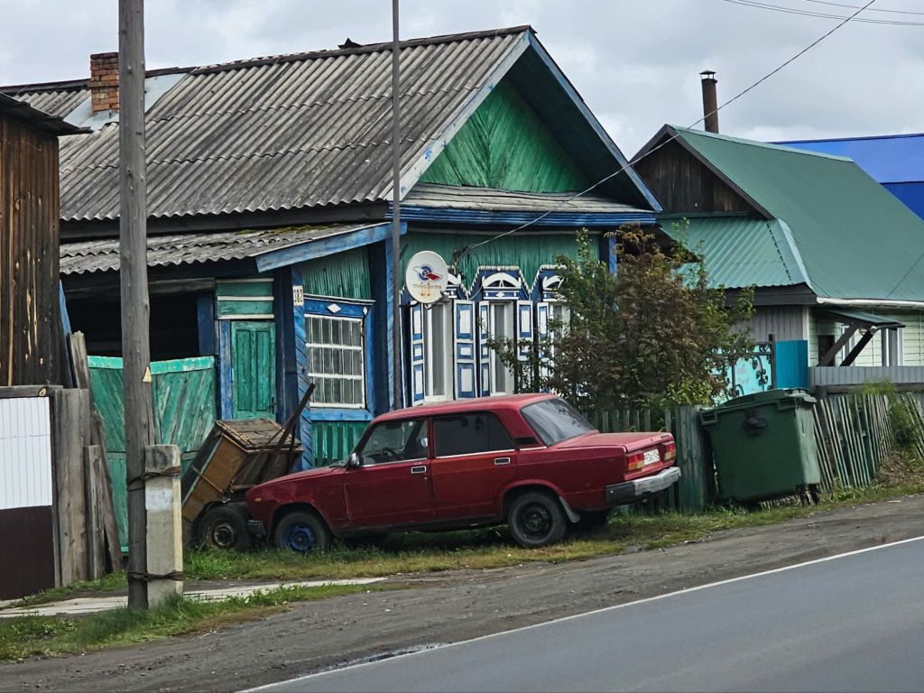 čevená lada zaparkovaná pred farebným dreveným domčekom