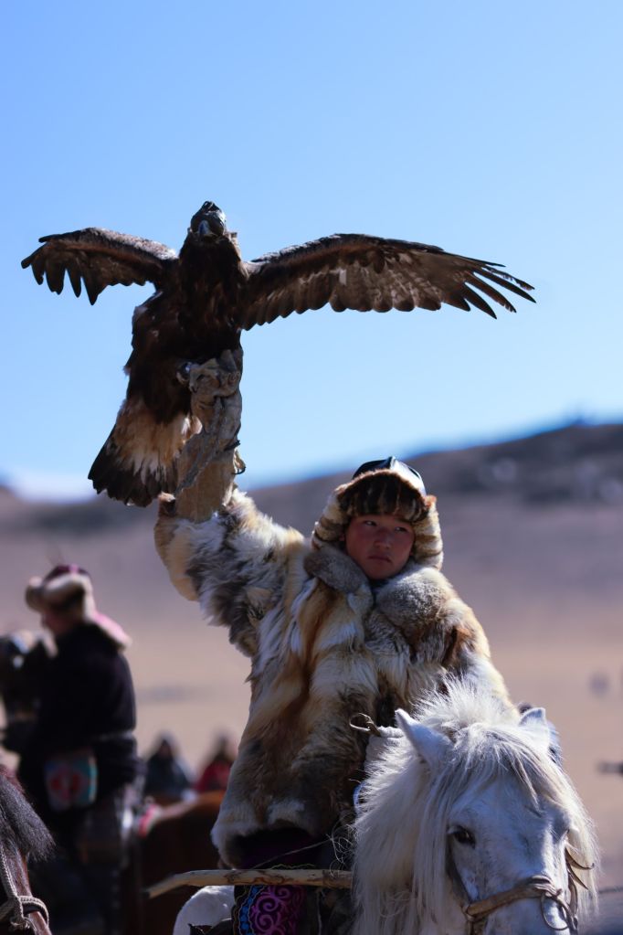 chlapec v kožuchu držiaci orla nad hlavou