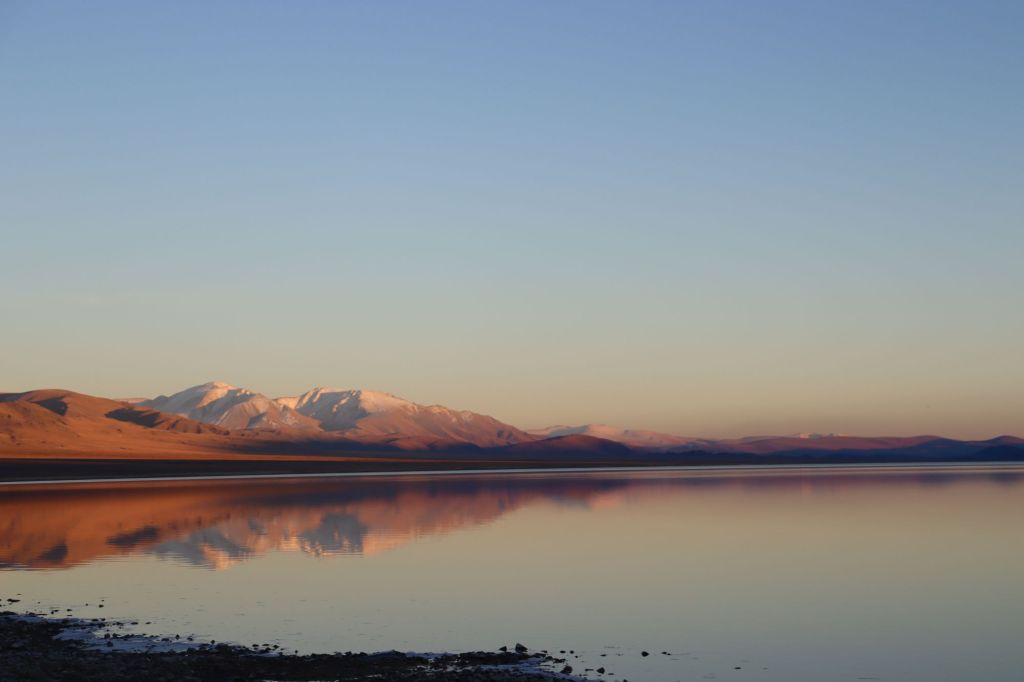 jazero a západ slnka. zasnežené koce odražajúce sa na hladine