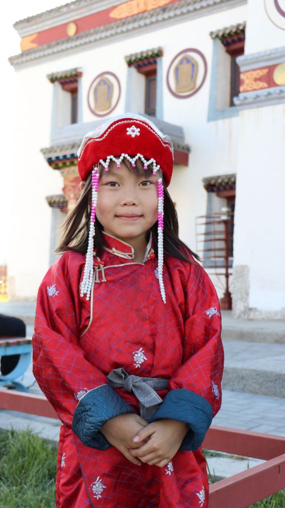 mongolské dievča v tradičnom červenom budhistickom oblečení pred kláštorom.